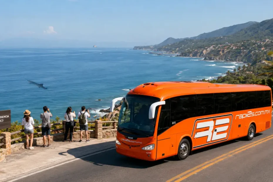 Autobús naranja de Rapi2s circulando por una carretera costera junto al Mirador Playa La Audiencia en Colima, mientras turistas observan el mar.